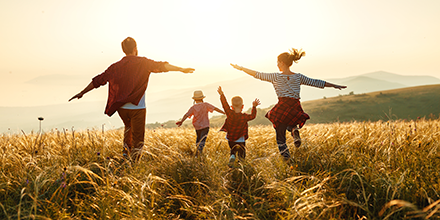 a family playfully running through a wheatfield while the sun sets